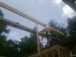 Carpenter setting a ridge beam over a new addition frame — Ice Dam Removal by Roofing Brothers in Avella