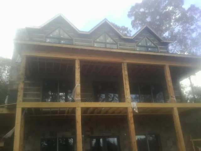 Dormers and porch framing on a large log home under construction — Roof Coating work by our crew in Avella