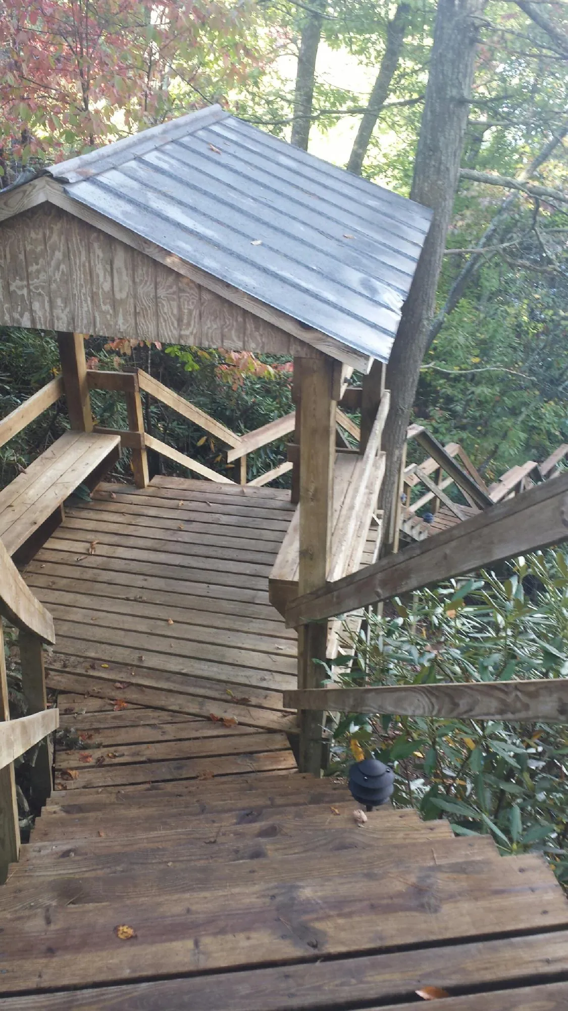 Metal roofed shelter over wooden steps on a wooded walkway — Skylight Repair & Installation work by our crew in Avella