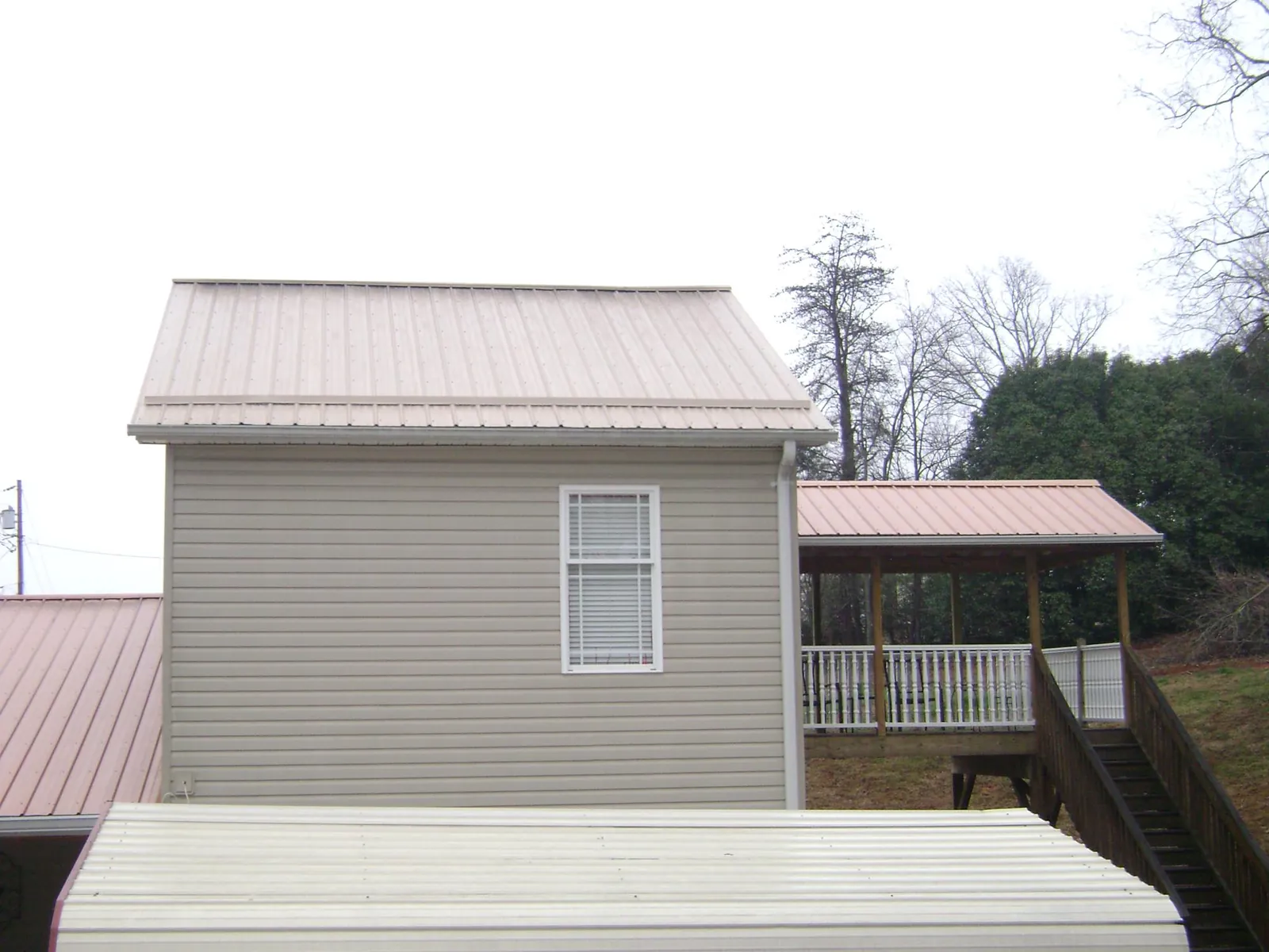 Tan metal roofs on a two story addition and attached porch, from a Roof Replacement job in Avella