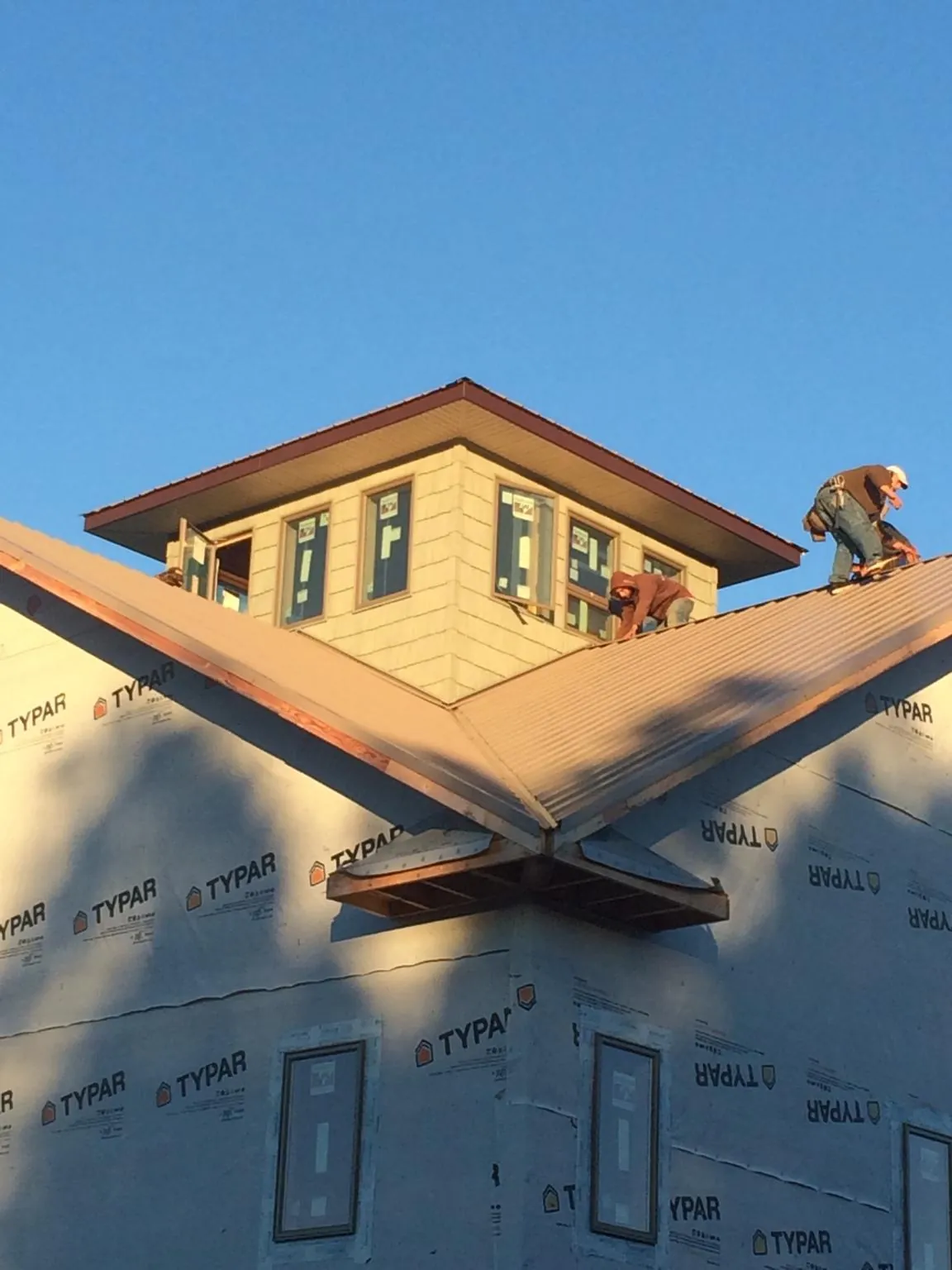 Roofers working around a rooftop cupola on a new metal roof at sunset — Roof Waterproofing in Avella by Roofing Brothers